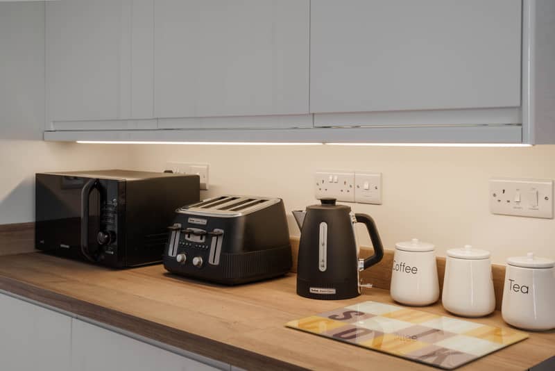 Kitchen worktop with kettle, toaster and microwave under lit cabinets