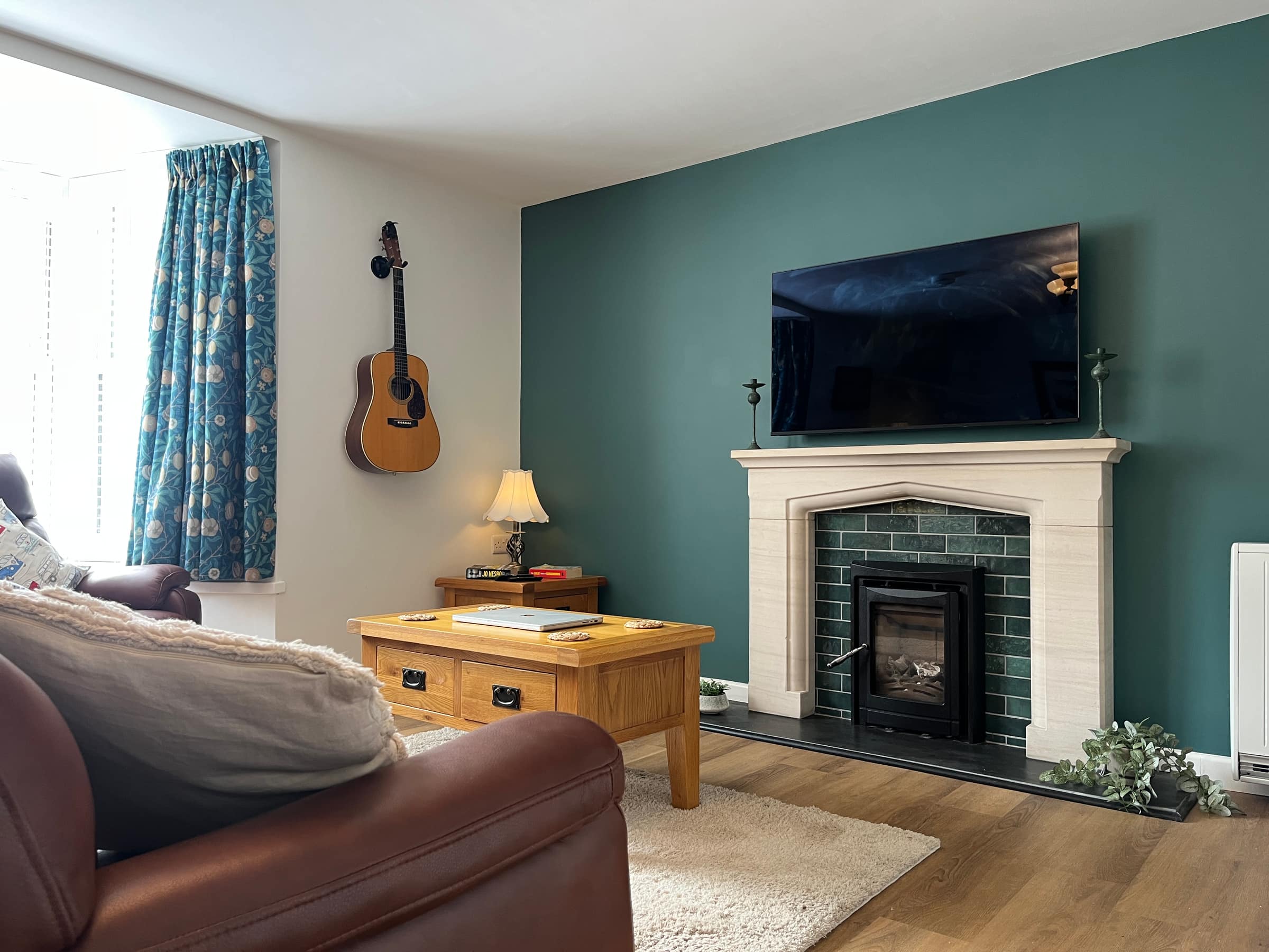 The sitting room of the Courtyard Apartment, with leather sofa, armchair and feature fireplace