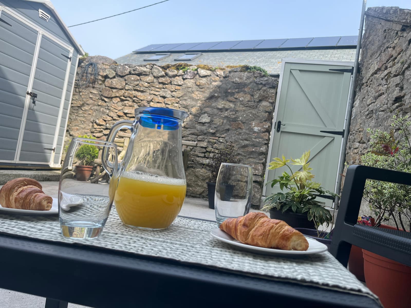 Croissants and a jug of orange juice on a table in the granite-walled courtyard
