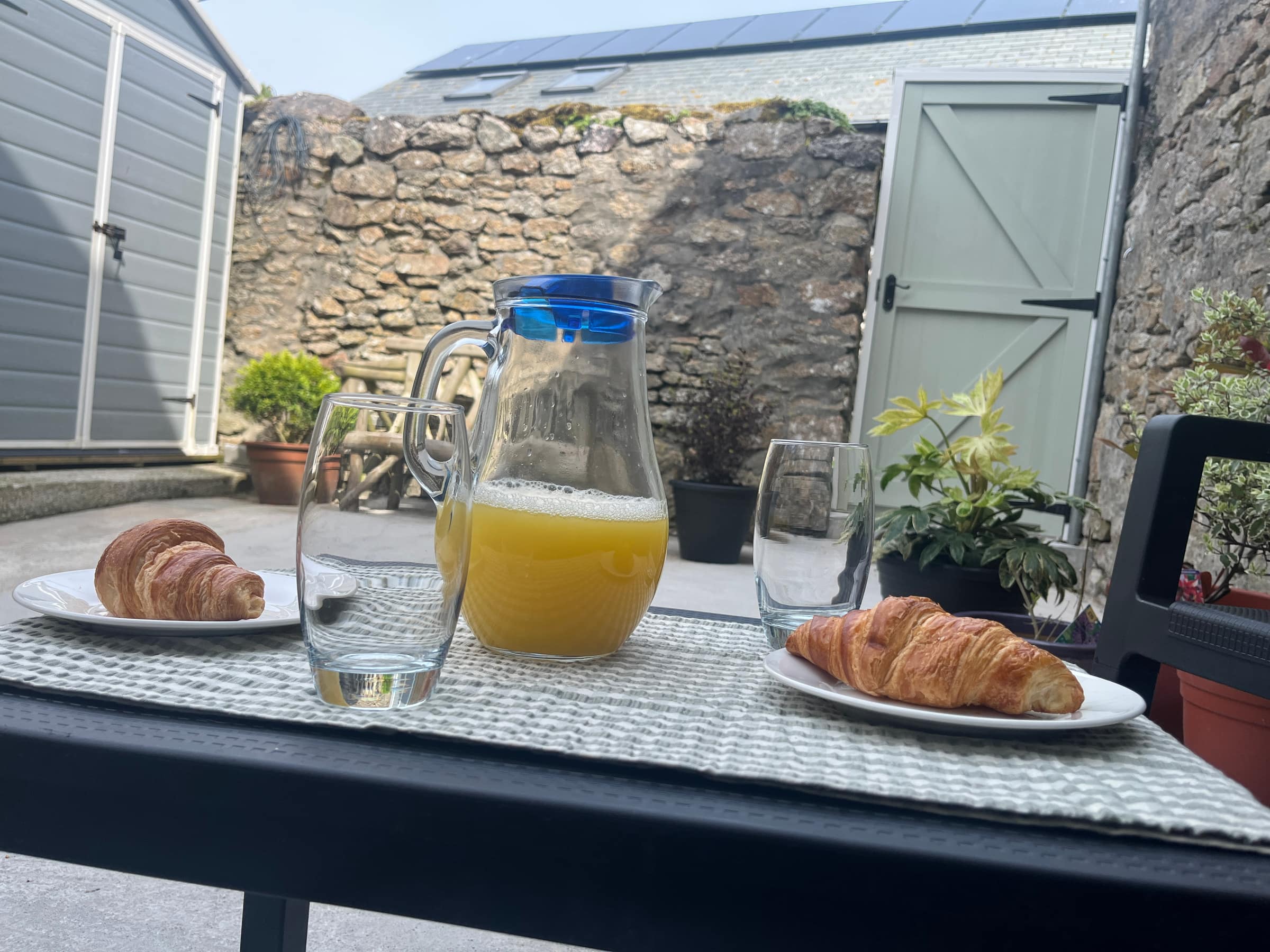 Breakfast of croissants and orange juice laid out in the granite-walled courtyard