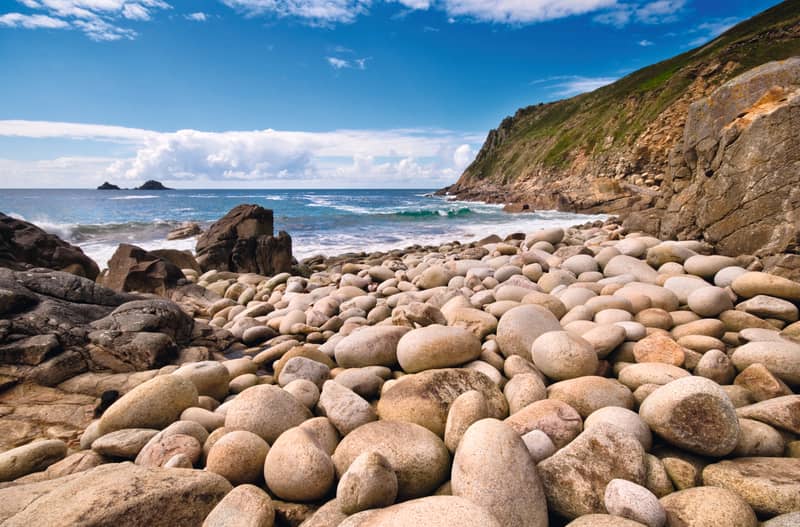 The famous rounded granite boulders of Porth Nanven beach with the Brisons rocks offshore