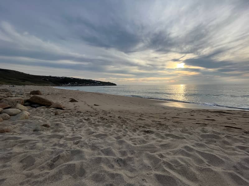 Sennen beach at dusk with the tide washing in over golden sand