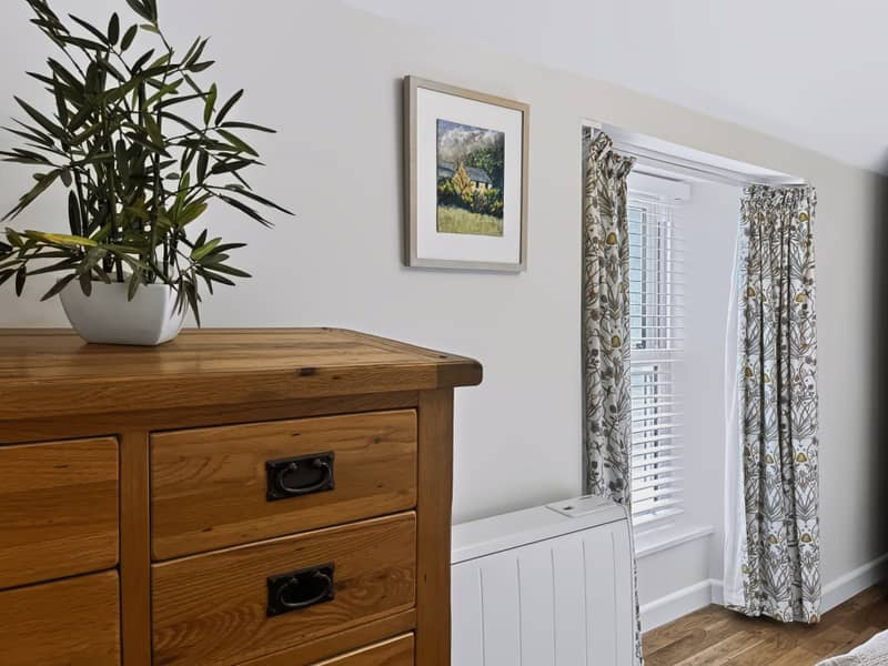 Oak chest of drawers and framed painting in the bedroom
