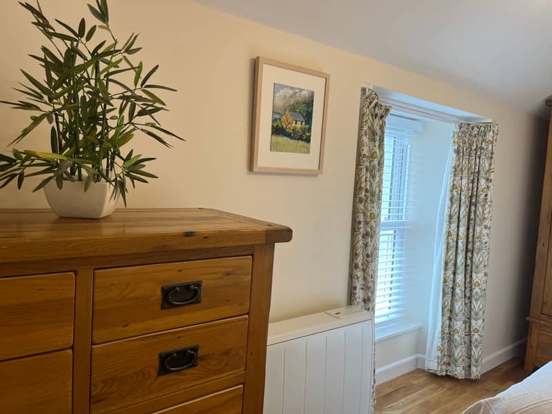 Bedroom with oak chest of drawers and floral curtains