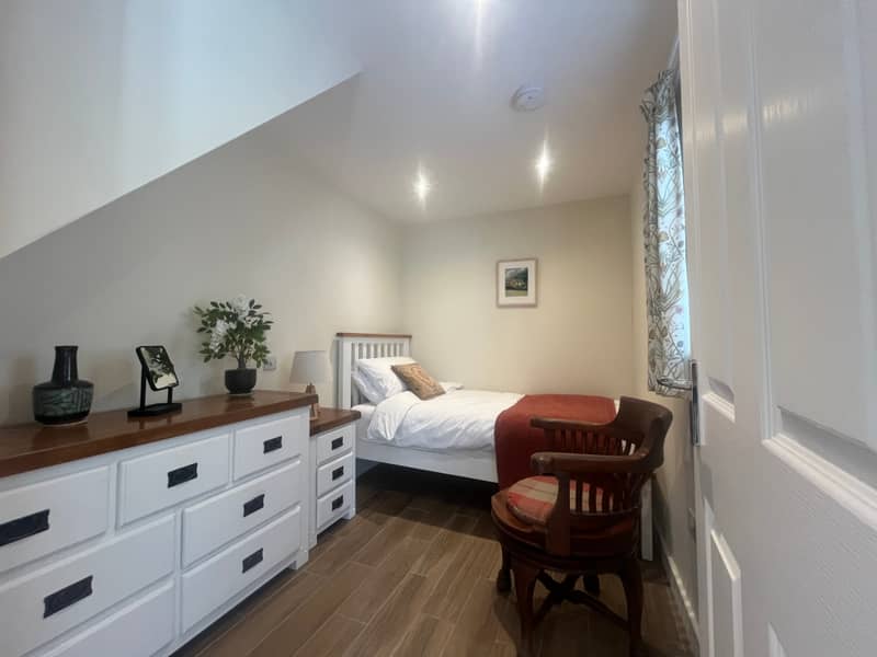 Single bedroom with white furniture and armchair