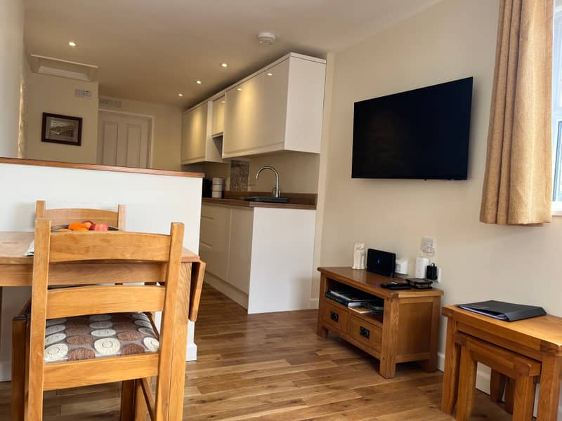 Open-plan living space with dining table, TV and kitchen beyond